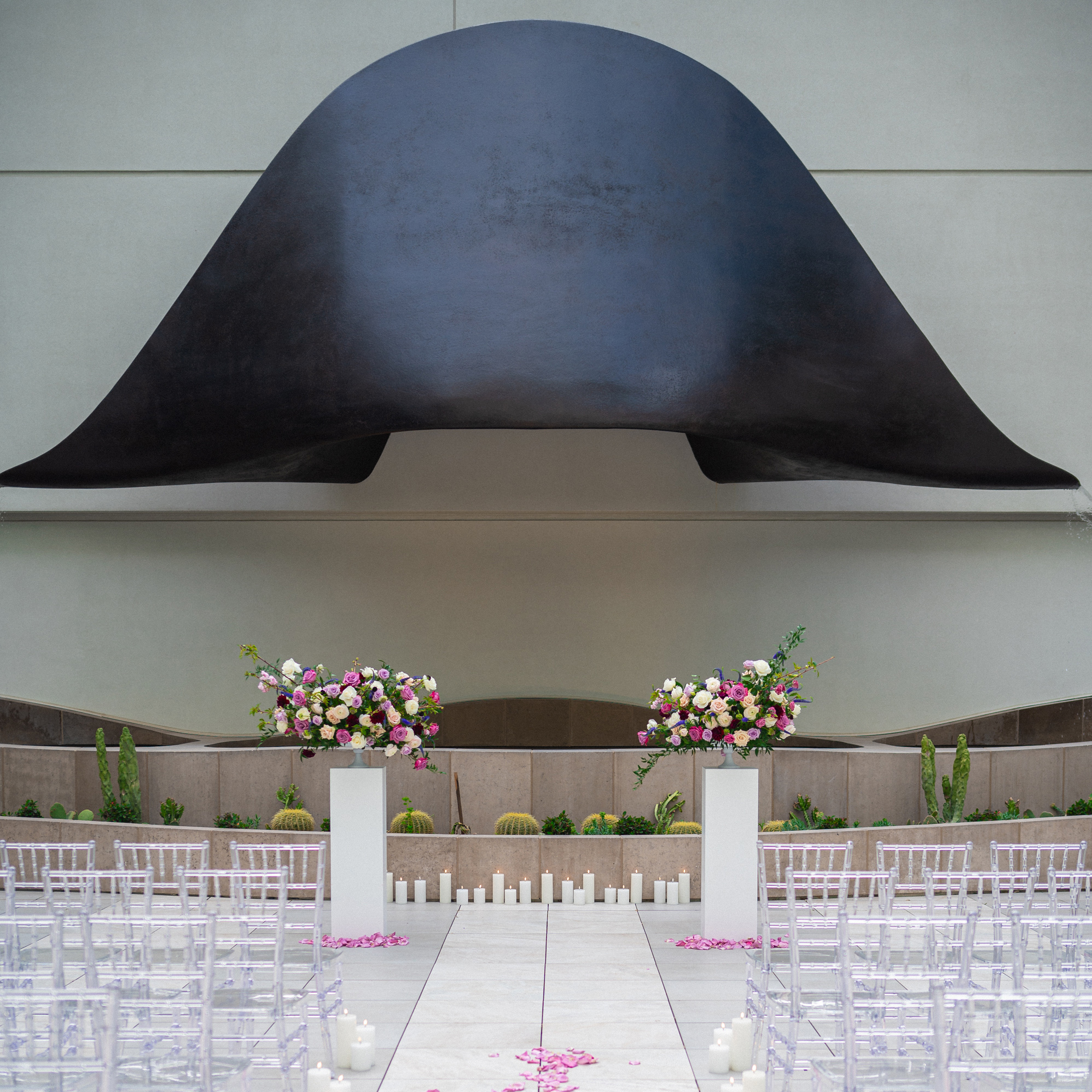 Hat art piece framing a pathway with flower petals and seating.