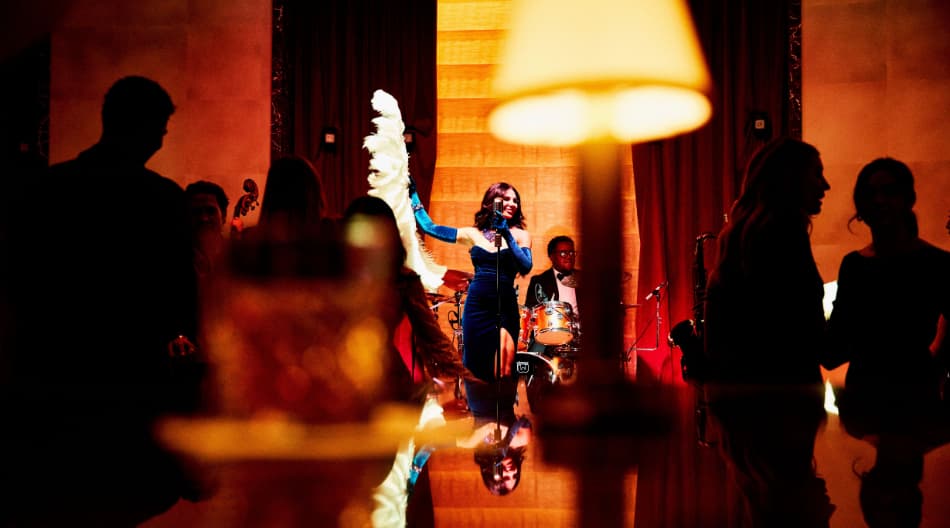 Mikalah Gordon holding a white feather fan in a blue dress through a crowd